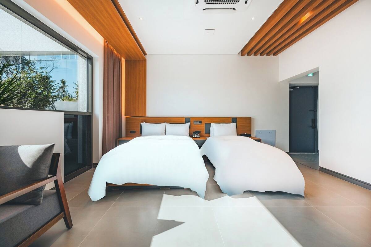 A modern bedroom with a large bed, a bedside table, and a chair.