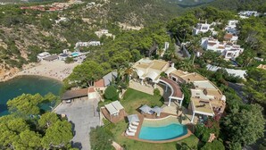 Vista aérea de una propiedad costera con piscina, varias construcciones y una playa.