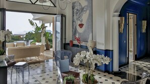 Un amplio salón con un gran ventanal, una araña y una obra de arte moderna en la pared.