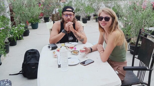Two people sitting at an outdoor table with potted plants around them. - Guest House UGS  (Jodhpur)