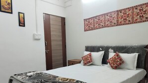 A bedroom with a bed, a wardrobe, and a decorative wall hanging. - Guest House UGS  (Jodhpur)