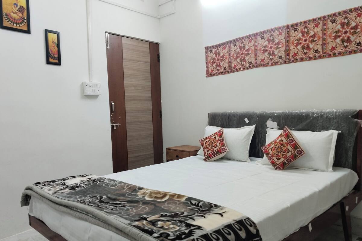 A bedroom with a bed, a wardrobe, and a decorative wall hanging.
