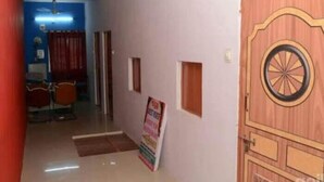 A hallway with a wooden door, a small window, and a poster on the wall. - Guest House UGS  (Jodhpur)
