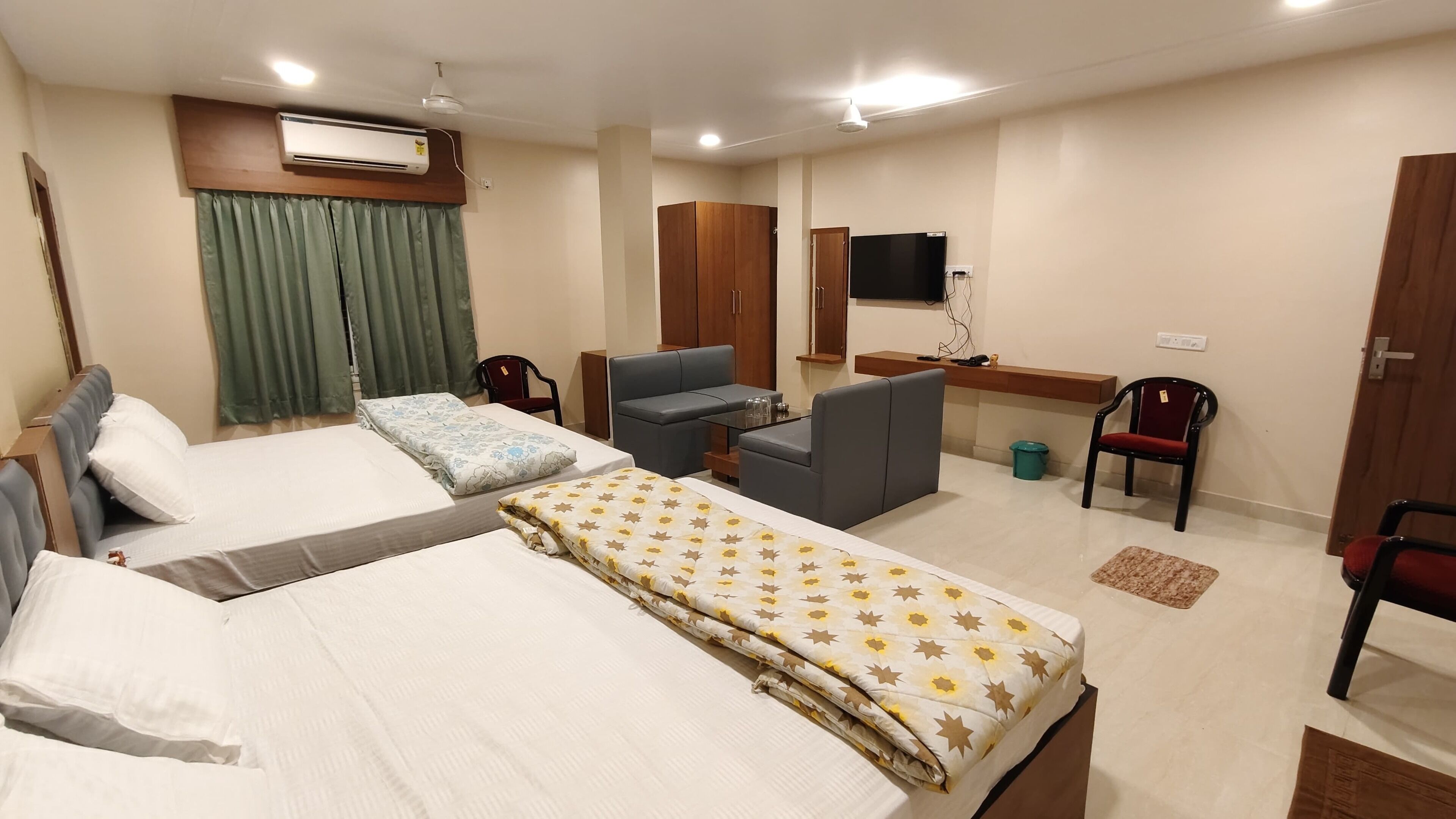 A hotel room with two beds, a desk, a chair, a TV, and a wardrobe.