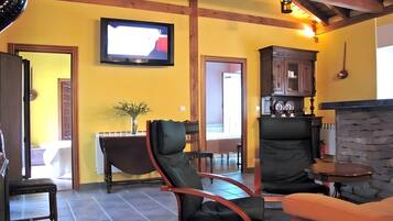 A living room with a television, a fireplace, a dining area, and a kitchen.
