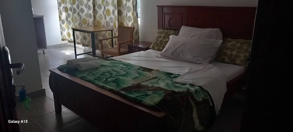 Ein Hotelzimmer mit einem Bett, einem Sessel, einem Tisch und einem Vorhangfenster.