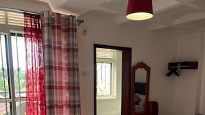 Un salon avec un canapé beige, un meuble en bois et une lampe suspendue rouge.