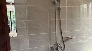 Une salle de bain avec une douche, des toilettes et une fenêtre.