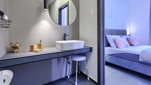 A modern bathroom with a white sink, a round mirror, and a toilet. - Apartment Cintya by Interhome (Poreč)