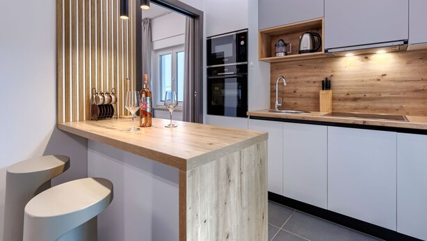 A modern kitchen with a wooden countertop, stainless steel appliances, and a built-in wine rack. - Apartment Cintya by Interhome (Poreč)