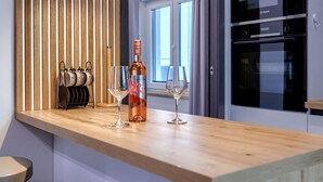 A modern kitchen with wooden cabinetry, a wine bottle, and two wine glasses on the counter. - Apartment Cintya by Interhome (Poreč)