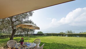 An outdoor patio with a round table, four chairs, and a striped umbrella.