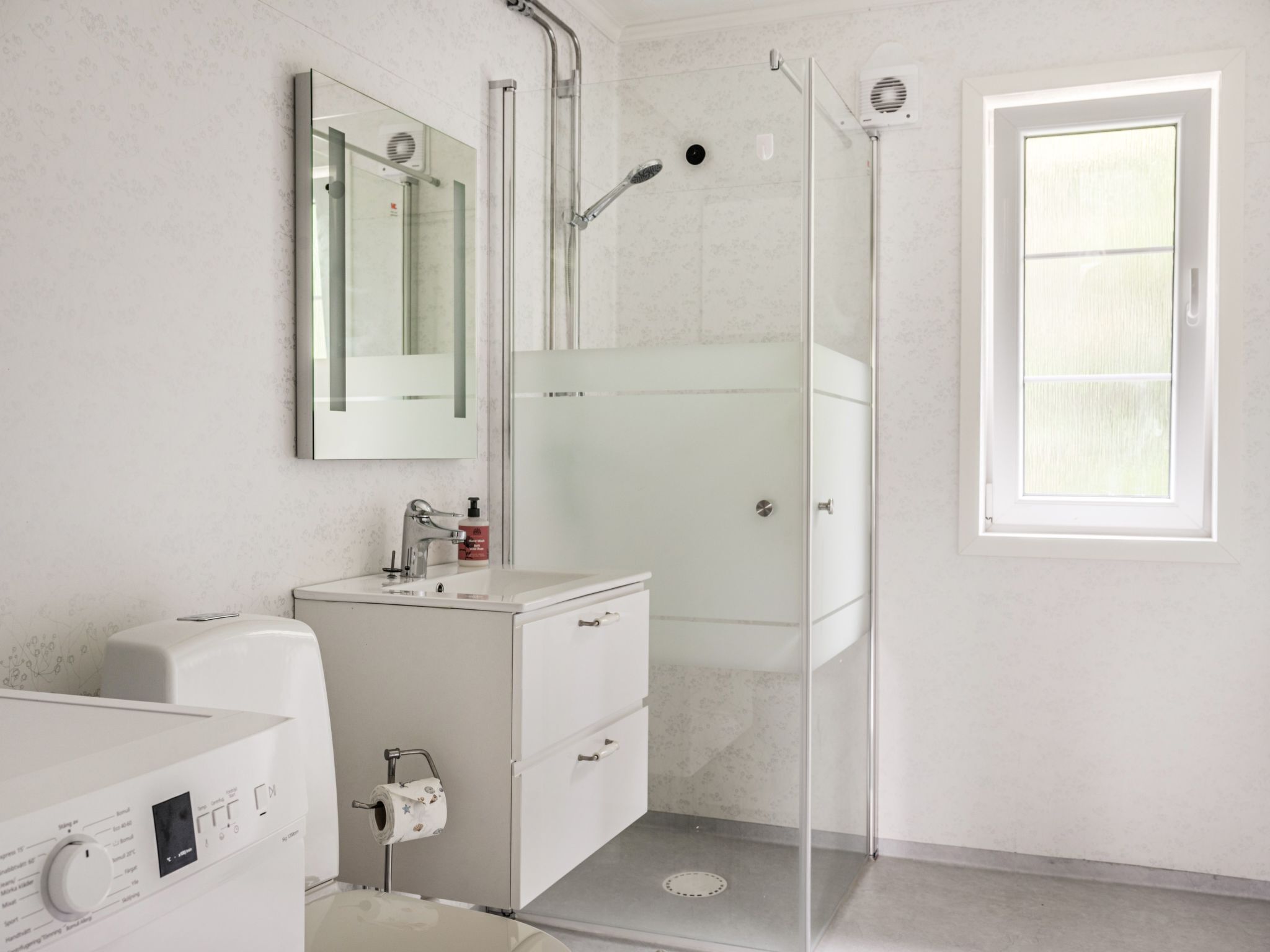 Une salle de bain moderne avec une douche à parois de verre, un meuble-lavabo avec un miroir et des toilettes.