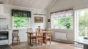 Una cocina con sillas de madera, una mesa de comedor y una ventana con vistas a follaje.