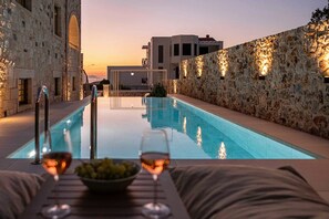 Blick auf einen Pool, eine Steinmauer, einen klaren Himmel und einen Sonnenuntergang.