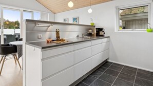 A modern kitchen with a wooden ceiling, a large island with a sink, and a window overlooking a deck. - "Lio" - 200m from the sea by Interhome (Bjert)