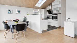 A modern kitchen with white cabinetry, a built-in oven, and a small refrigerator. - "Lio" - 200m from the sea by Interhome (Bjert)