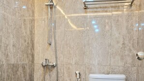 A bathroom with a shower, toilet, and a towel rack. - Royal Kencana Hotel (Jepara)