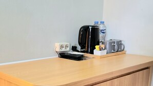 A wooden counter with a coffee maker, a kettle, a water bottle, and a mug. - Royal Kencana Hotel (Jepara)