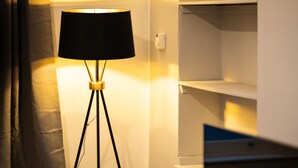 A floor lamp with a black shade in a room with white walls and shelves. - Court Street by Central Serviced Apartments (Dundee)