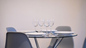 A dining table with four wine glasses and plates, set in a modern room with chairs. - Court Street by Central Serviced Apartments (Dundee)