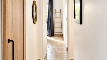 Un couloir avec une porte en bois, une échelle et un tableau encadré accroché au mur.