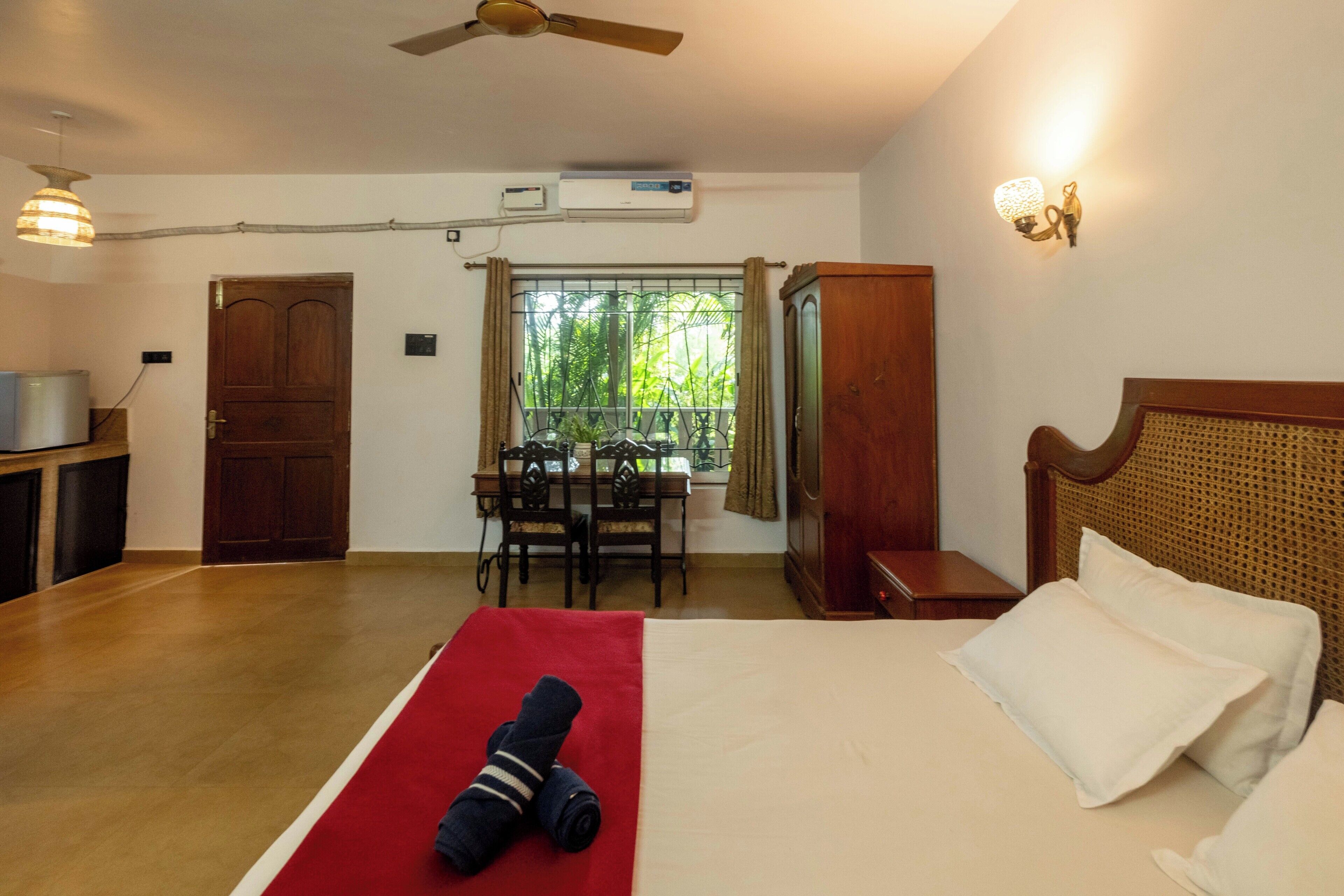Una habitación de hotel con cama, escritorio y ventana con vistas a zonas verdes.