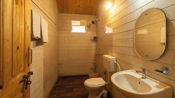 Un baño con paneles de madera, un inodoro, un lavamanos y un ventanal pequeño.