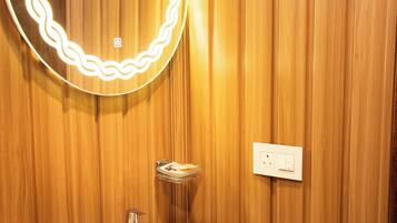 Un baño con pared de madera, un lavabo, un espejo con iluminación y un enchufe.