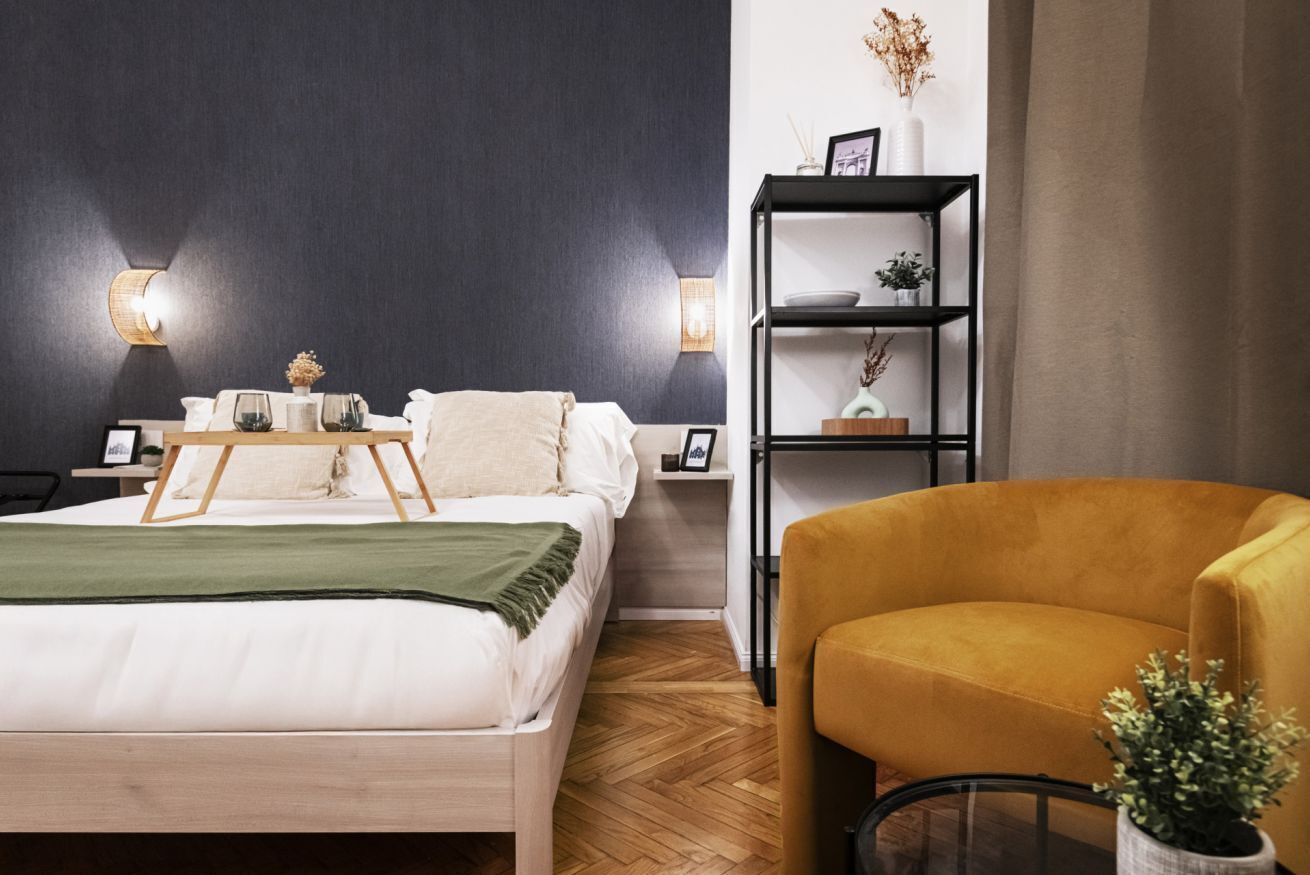 Une chambre à coucher comprenant un lit, des tables de chevet, une commode, une bibliothèque et une chaise.