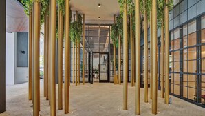 A spacious lobby with a herringbone floor pattern, tall golden pillars, and green plants hanging from the ceiling. - NEW Stunning 2/2 with Panoramic Views of Miami PH Condo 50th floor (Miami)