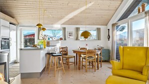 A modern kitchen with wooden cabinets, a dining area with wooden chairs, and a yellow armchair. - Stunning home in Haderslev with WiFi (Haderslev)