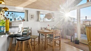 A cozy dining area with wooden furniture, a round table, and chairs. There is a window with curtains, a hanging light fixture, and a view of the outdoors. - Stunning home in Haderslev with WiFi (Haderslev)
