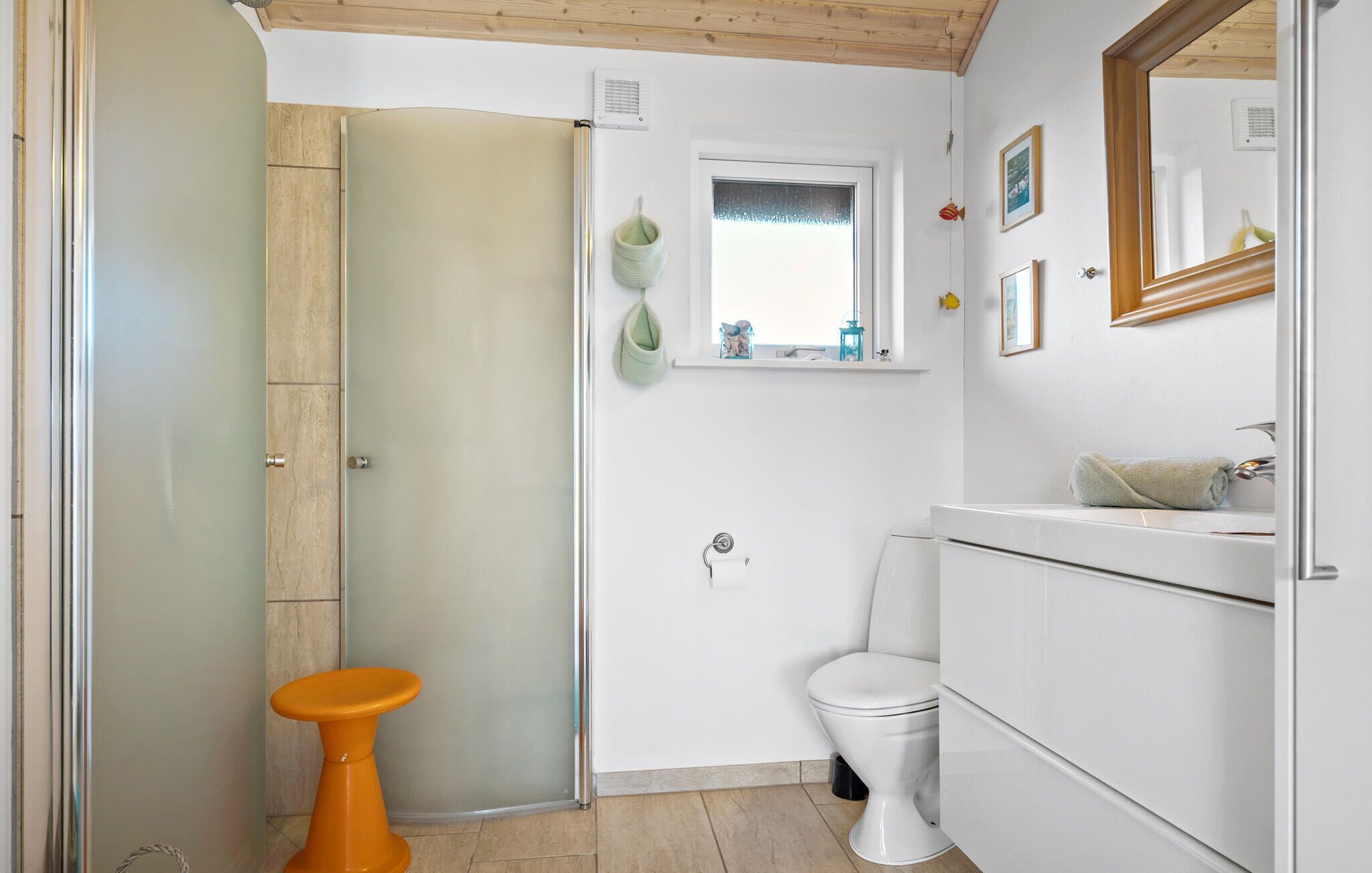 Un baño con inodoro blanco, lavamanos con espejo y zona de ducha.