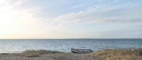 A beach with a boat on the sand and the ocean in the background.