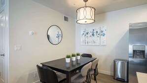 A modern kitchen with a dark wooden table, grey chairs, a stainless steel refrigerator, and a hanging light fixture. - 6G Moab RedCliff Condo, POOL & HOT TUB (Moab)