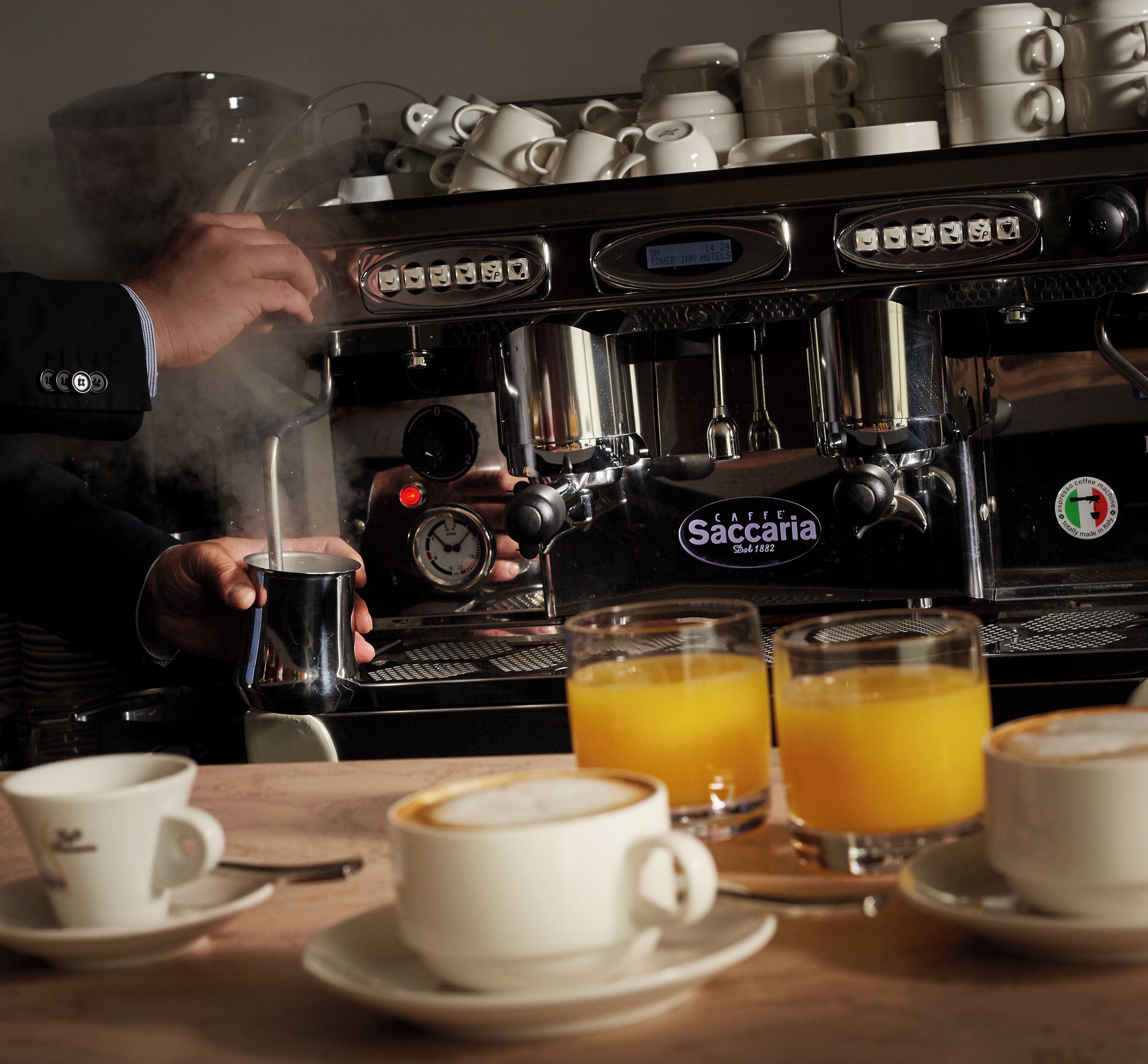 Una máquina de café con vapor, un temporizador y una taza de café sobre una mesa.