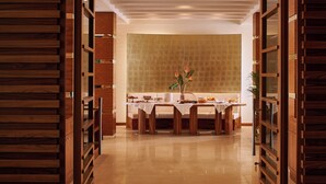 A dining area with a wooden table set for a meal, a large window with a textured wall behind it, and wooden paneling on the walls. - Hotel PisaValdera (Pontedera)