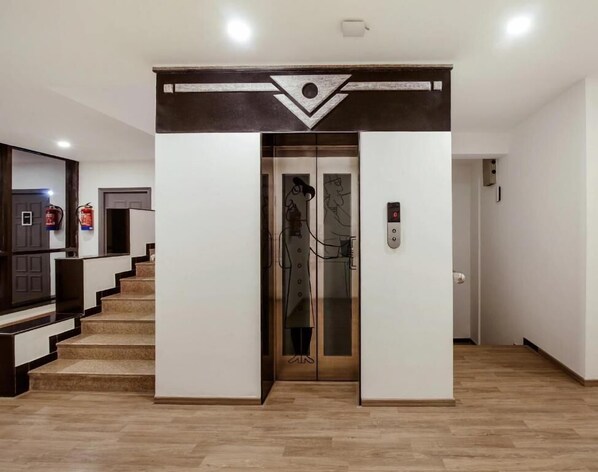An elevator entrance with a modern design, a fire extinguisher on the wall, and a staircase leading to another floor. - The Onyx (Nagpur)