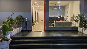 A hotel entrance with a reception desk, potted plants, and a staircase leading inside. - The Onyx (Nagpur)