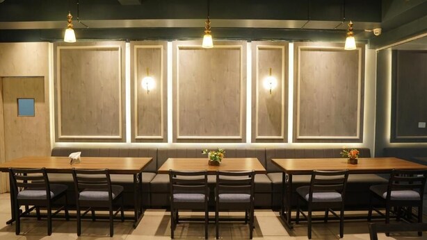 A restaurant with a long wooden table, multiple chairs, and pendant lighting. - The Onyx (Nagpur)