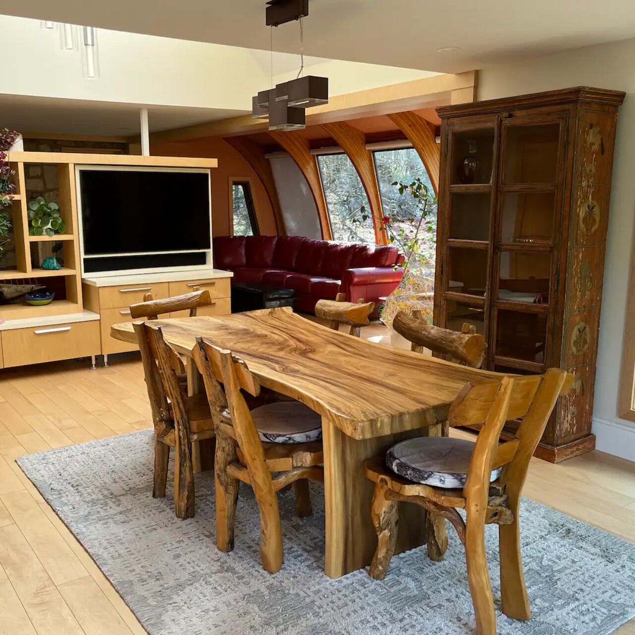 A dining area with a wooden table and chairs, a red sofa, and a television.