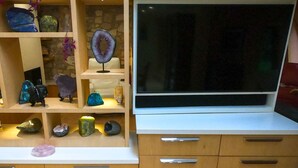 Ein modernes Unterhaltungssystem mit einem Flachbildfernseher, Regalen mit Dekorationen und Schubladen.