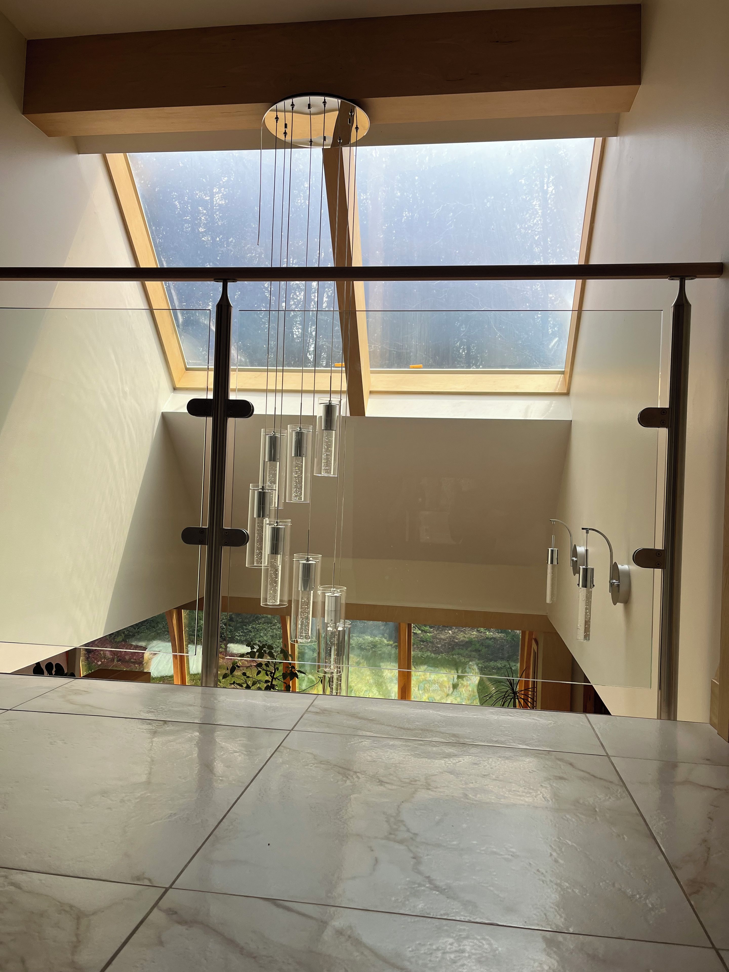Ein modernes Interieur mit Oberlicht, einer Pendelleuchte und Blick auf Grünflächen außerhalb.