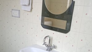 Un bagno con un lavabo bianco su piedistallo, uno specchio e un portasciugamani.