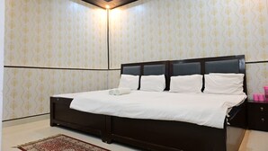 Una camera da letto con un letto grande, una testiera scura e carta da parati decorata.
