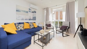 A modern living room with a blue sofa, two armchairs, a glass coffee table, and a floor lamp. - PROARQUINSA S.A. offers you temporary luxury apartments in Madrid.   (Madrid)