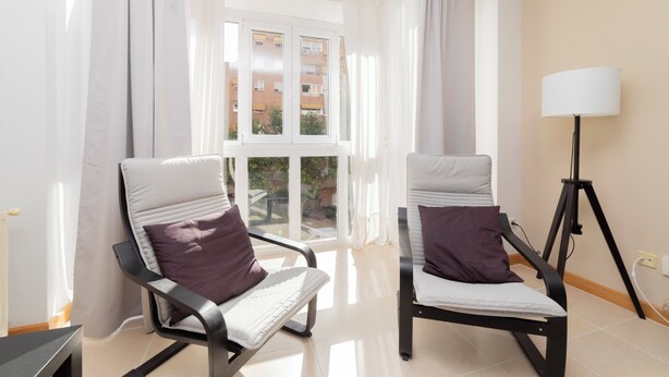A room with two reclining chairs, a standing lamp, and a large window with curtains. - PROARQUINSA S.A. offers you temporary luxury apartments in Madrid.   (Madrid)