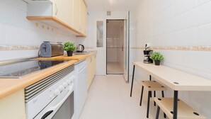 A compact kitchen with a stove, oven, and a small dining table with chairs. - PROARQUINSA S.A. offers you temporary luxury apartments in Madrid.   (Madrid)