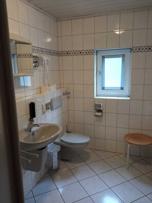 Et badeværelse med vask, toilet og et vindue.